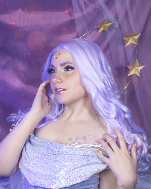 a portrait of a woman with purple hair and a halo of stars looking up